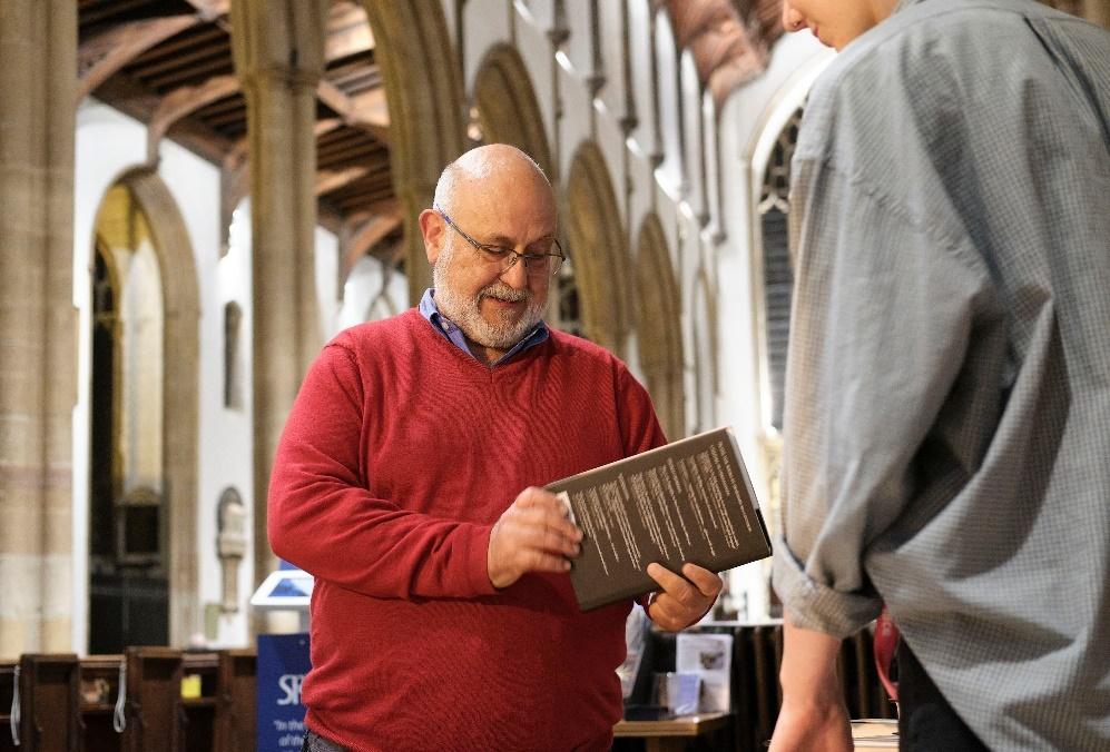 Alan Whiteside holding a book, standing inside St Mancroft Church