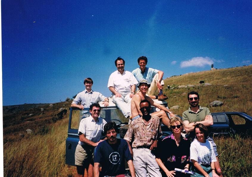 A group of men sat on top of and surrounding a Land Rover, in Malolotja National Park