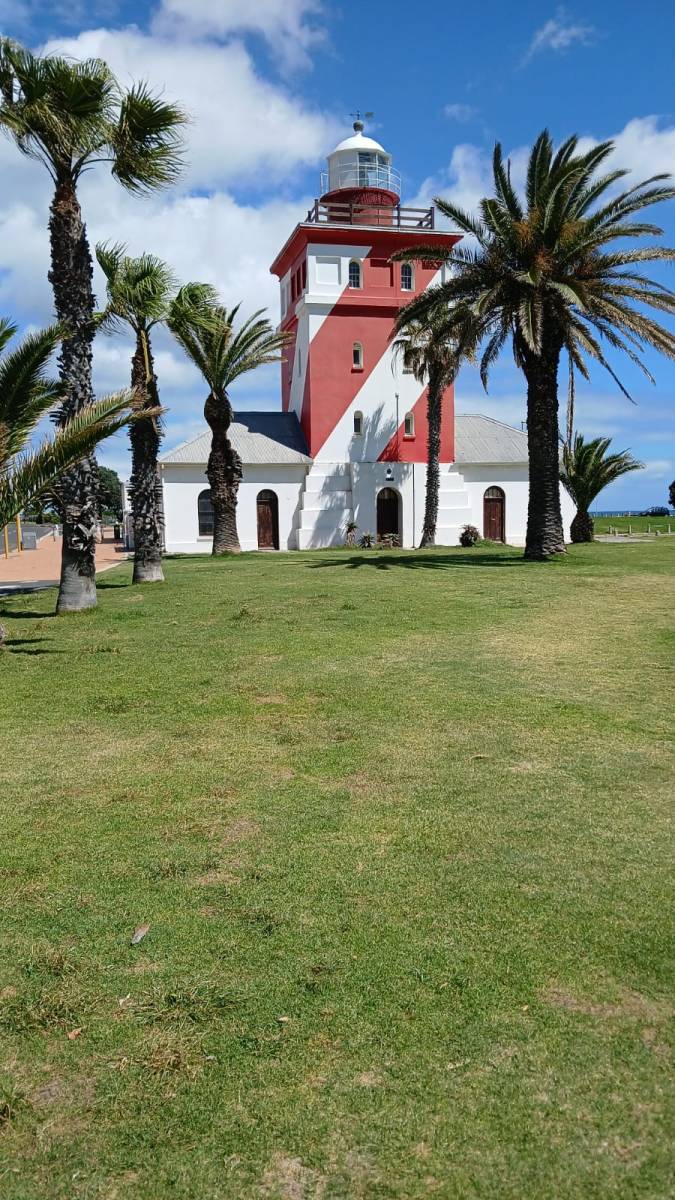 A red-and-white striped, behind a lawn, on a sunny day