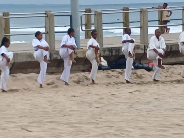 A group of women on a beach practicing Karate.